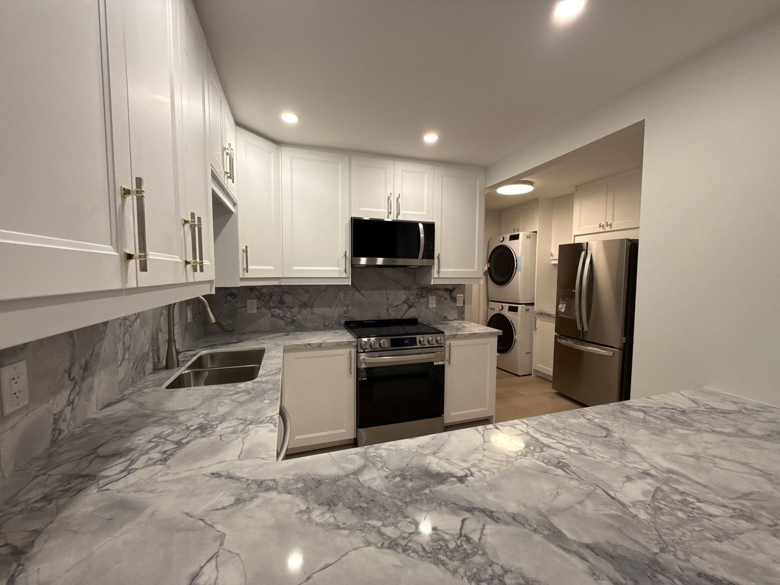 Basement kitchen with marble waterfall counter and laundry